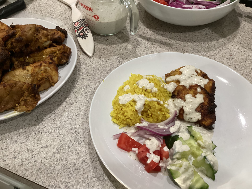Dianne's Mediterranean chicken and yellow rice plate with cucumber, tomato, red onion, and creamy white sauce