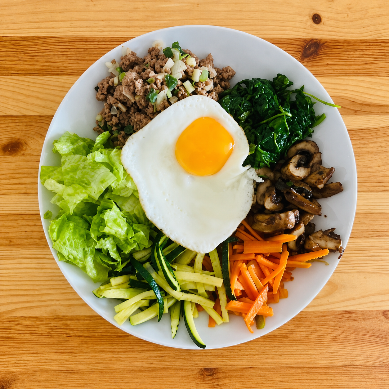 A colorful protein-forward small plate with egg, vegetables, greens, mushrooms, and ground protein